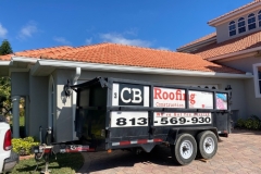 A CB Roofing dump trailer on a roofing jobsite.