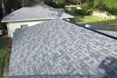 A close-up view of a roof repair job with gray architectural shingles on a home in Tampa, Florida.
