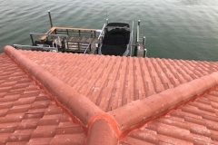 Aerial view of a Florida home with a new terracotta tile roof with a boat dock on the water in the background.